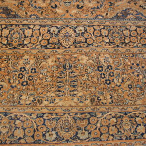 Detailed view of a rug showing intricate floral patterns in rust, gold, navy, and light blue borders.