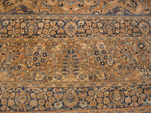 Detailed view of a rug showing intricate floral patterns in rust, gold, navy, and light blue borders.