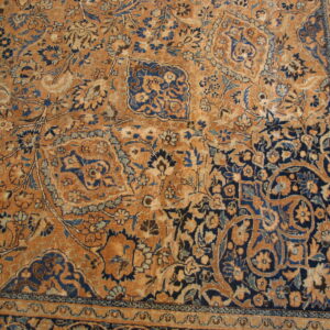 Rust and indigo rug with detailed floral and vine patterns and a visible ornamental border.