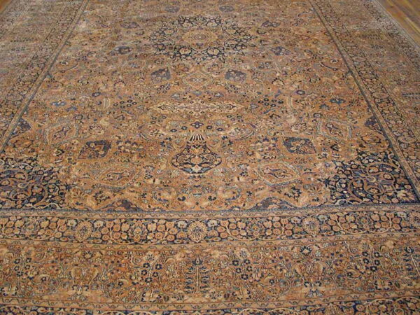 Low-pile rug in golden tan and navy blue with a detailed traditional floral medallion design.