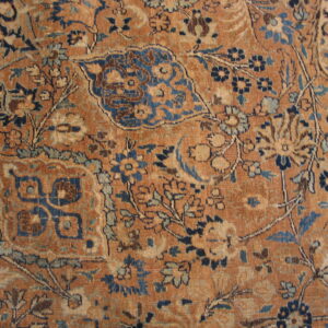 This rust-colored low pile rug displays distressed floral and palmette designs in blues and creams.