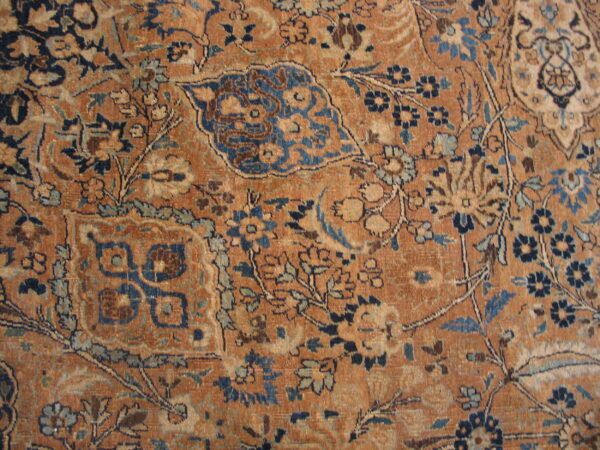 This rust-colored low pile rug displays distressed floral and palmette designs in blues and creams.