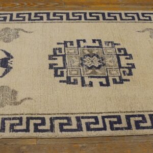 Cream runner rug featuring navy geometric borders and grey motifs rests on wood plank flooring.