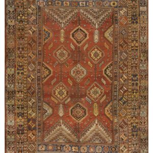 Red geometric rug with tribal diamond motifs, visible wear, and complex multicolored borders.