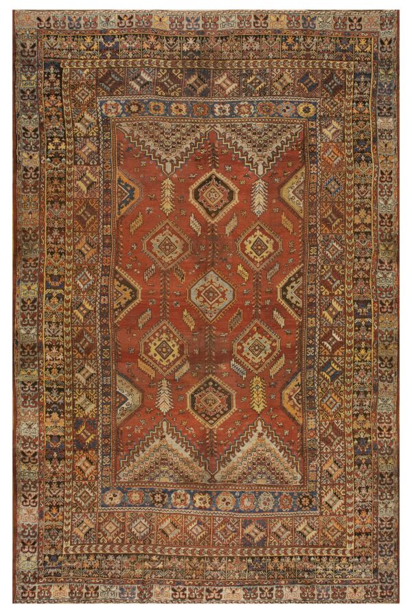 Red geometric rug with tribal diamond motifs, visible wear, and complex multicolored borders.