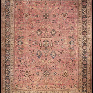 Dusty pink traditional rug with dense floral pattern and wide navy blue and tan ornamental borders.