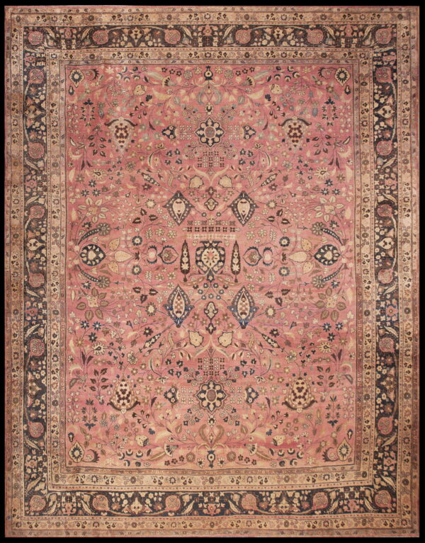 Dusty pink traditional rug with dense floral pattern and wide navy blue and tan ornamental borders.
