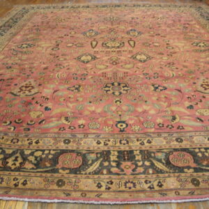 Large low-pile rug with a rose field and intricate blue and beige floral patterns on wooden planks.