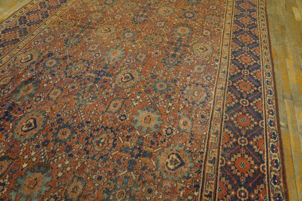 Intricate rust and navy rug featuring an all-over floral pattern and a wide decorative border on wood floors.