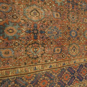 Distressed rug features detailed patterns in faded rust red, deep blue, and beige over hardwood floors.