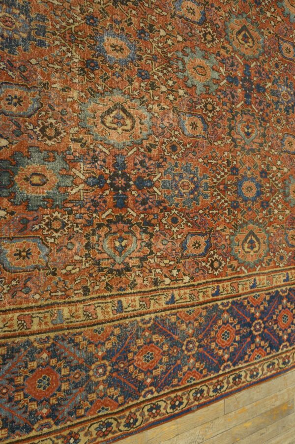 Distressed rug features detailed patterns in faded rust red, deep blue, and beige over hardwood floors.