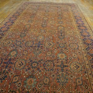 Long low-pile rug featuring dense patterns in rust, navy, and pale blue on distressed wood floors.