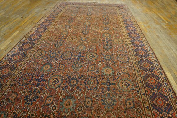 Long low-pile rug featuring dense patterns in rust, navy, and pale blue on distressed wood floors.