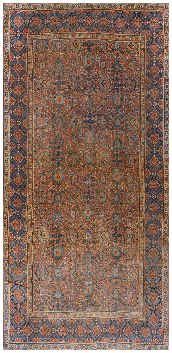 Muted rust and navy rug with low pile, featuring intricate geometric and stylized floral motifs.
