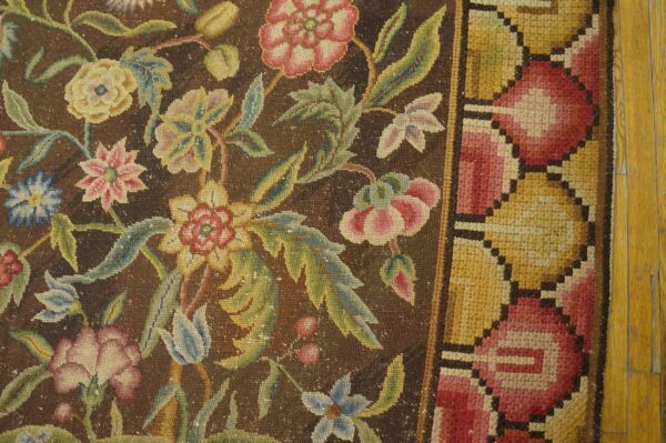 Dark brown low-pile rug featuring pink, yellow, and green floral designs next to light wood flooring.
