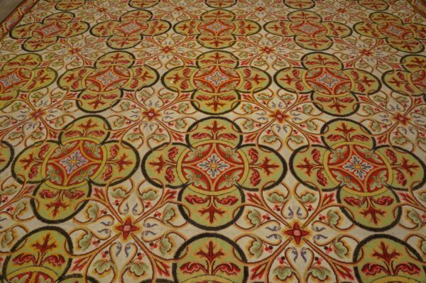 Highly patterned low-pile rug with interlocking red, gold, and olive green medallions on a cream background.