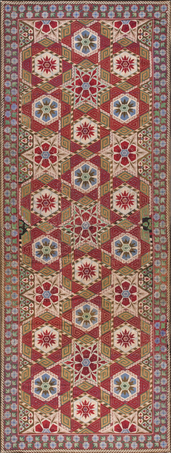 A detailed textile with red, cream, green, and blue geometric patterns featuring hexagonal star motifs.