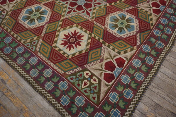 Low-pile rug with geometric and floral medallions in rich colors rests on distressed gray wood flooring.