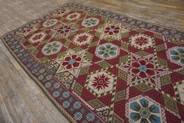 Geometric flatweave rug in red, blue, green, and tan colors laid diagonally across distressed wood floorboards.