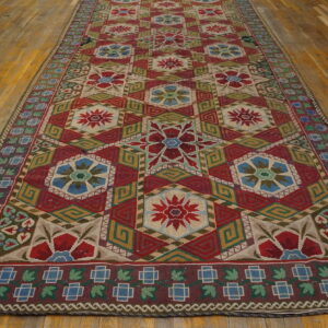 Flatwoven runner with red, blue, green, and beige geometric medallions displayed on distressed wood floors.