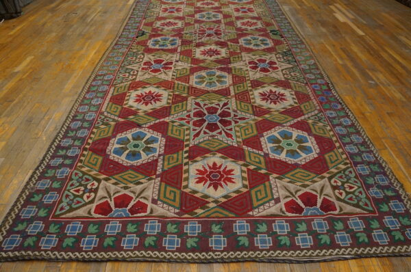 Flatwoven runner with red, blue, green, and beige geometric medallions displayed on distressed wood floors.