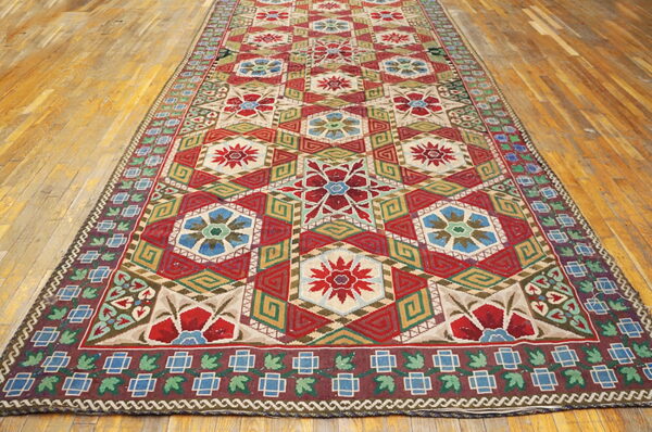 Runner rug with repeating red and blue hexagonal floral designs and complex borders on a wood floor.