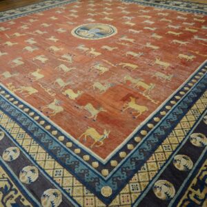 Distressed rust rug featuring yellow running animal motifs and a complex blue and indigo geometric border.