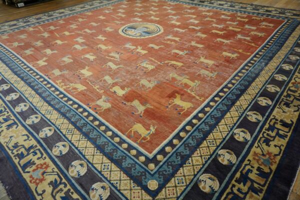 Distressed rust rug featuring yellow running animal motifs and a complex blue and indigo geometric border.