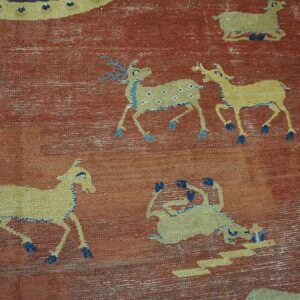 Distressed rust-colored rug featuring repeating yellow animal patterns detailed in light and dark blue.