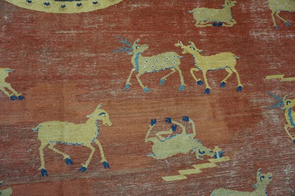 Distressed rust-colored rug featuring repeating yellow animal patterns detailed in light and dark blue.