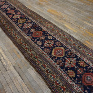 Navy blue runner rug with complex geometric patterns rests on a distressed gray wood floor.