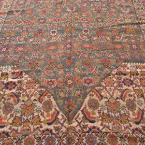 Detailed rug view showing teal and cream fields with dense floral patterns meeting in a point.