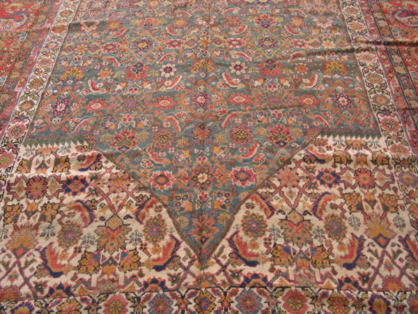 Detailed rug view showing teal and cream fields with dense floral patterns meeting in a point.