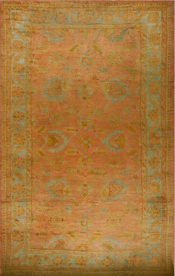 Faded coral and rust orange rectangular rug with an all-over traditional floral pattern in teal and gold.
