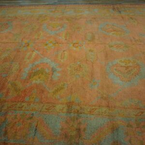Peach-toned low-pile rug with a traditional floral pattern in sage green and pale yellow on wood floors.