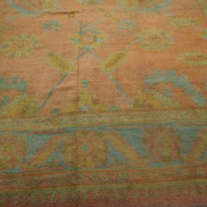 Textured rug detail showing a peach field and faded floral patterns in blue and soft yellow.