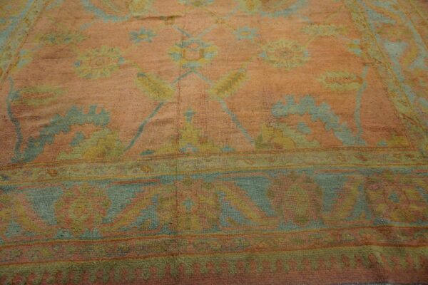 Textured rug detail showing a peach field and faded floral patterns in blue and soft yellow.