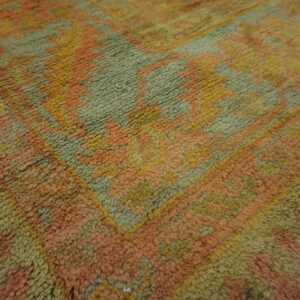 High-pile rug featuring a large geometric pattern rendered in peach, olive green, and gold.