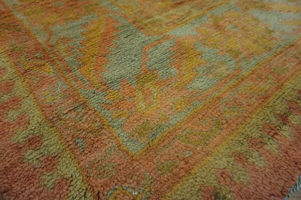 High-pile rug featuring a large geometric pattern rendered in peach, olive green, and gold.