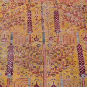 Ocher field rug with distressed texture and vertical columns of maroon and pink stylized trees.