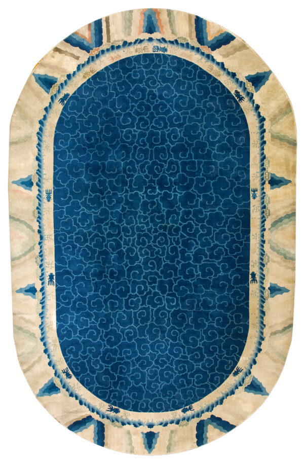 Oval blue rug with an all-over cloud pattern and a wide beige border featuring blue waves and creatures.