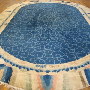 Large oval rug with a blue cloud motif field and a wide cream, pink, and blue decorative border.