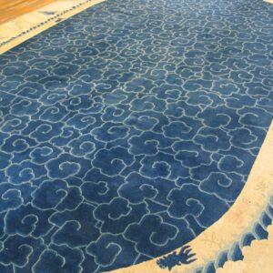 Indigo blue rug featuring a dense repeating cloud pattern outlined in light blue and a wide, curved cream border.