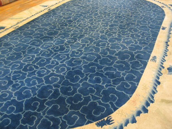 Indigo blue rug featuring a dense repeating cloud pattern outlined in light blue and a wide, curved cream border.