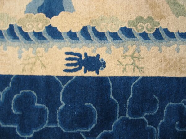 Plush rug detail featuring blue waves, beige clouds, a stylized creature, and dense indigo scrollwork.