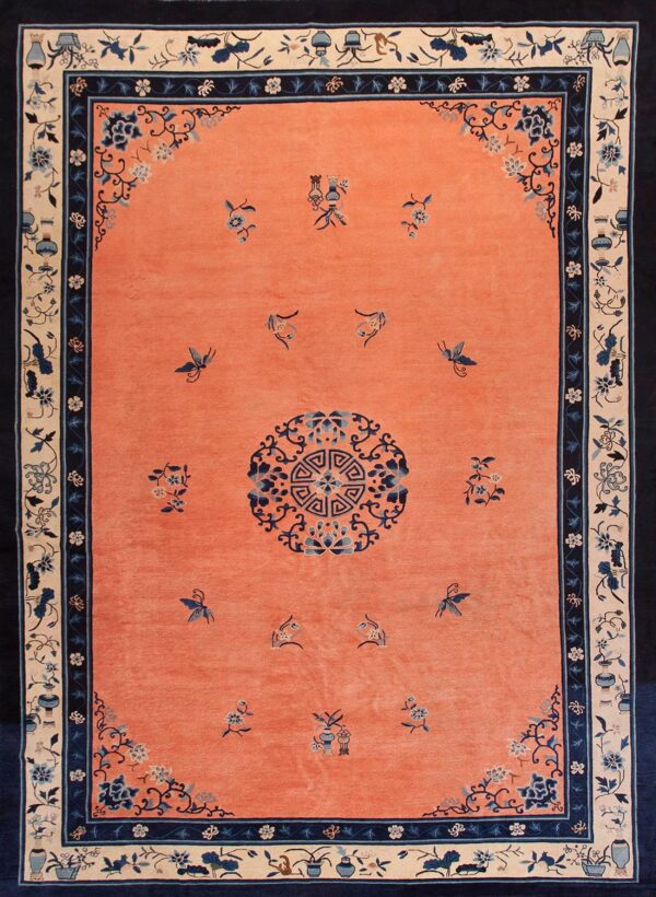 Coral rug with blue scattered floral and butterfly patterns, surrounded by detailed cream and navy borders.