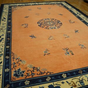 Coral field rug with scattered blue butterflies, a medallion, and wide navy and cream floral borders.