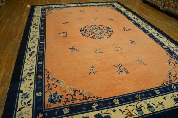 Coral field rug with scattered blue butterflies, a medallion, and wide navy and cream floral borders.