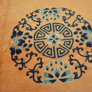 Plush peach rug detail showing a round geometric and floral medallion in navy and teal blue.