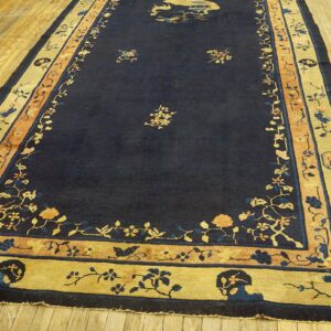 A long navy rug featuring gold and peach floral borders lies on a polished light wood floor.